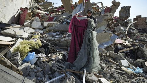 Nour Abu Al Zamar salvage items from under the rubble of her destroyed family home, in Rafah, southern Gaza Strip, Tuesday, Jan. 21, 2025, days after the ceasefire deal between Israel and Hamas came into effect. (AP Photo/Abdel Kareem Hana)