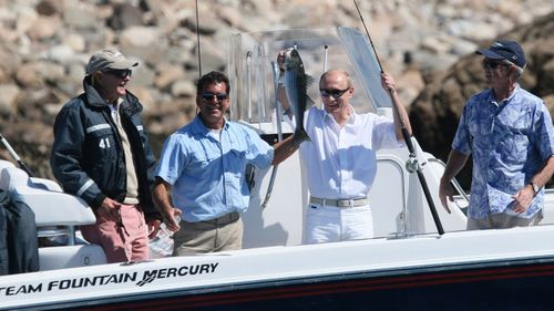 Russian President Vladimir Putin, second right, holding up his catch, as, from left, former President George H.W. Bush, fishing guide Billy Bush, and President Bush, right, look on, in 2007, in Kennebunkport, Maine.