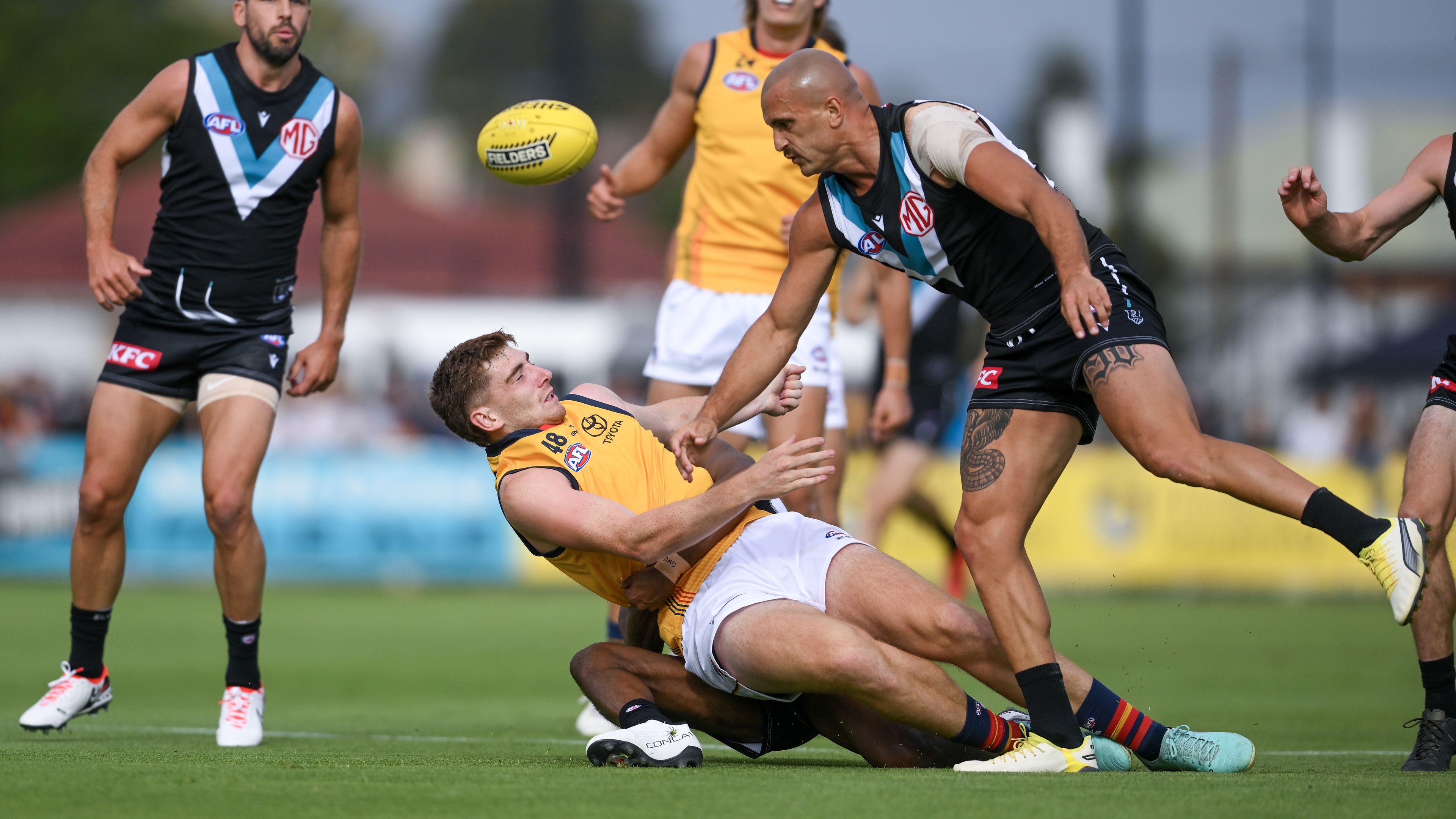 Mark Keane of the Crows  tackled by Willie Rioli of the Power and Sam Powell-Pepper of the Power causing a concussion during an AFL practice match.