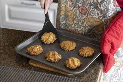 Homemade anzac biscuits being transferred onto a cooking rack.