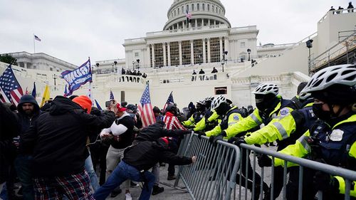 Trump supporters try to break through a police barrier.