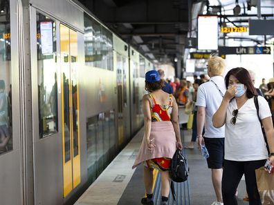 Sydney, Australia - March 1, 2020: Circular Quay, young Asian woman wearing face mask and other people waiting to board train at Circular Quay train station