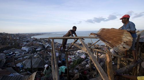 Men attempt to fix corrugated roofing to the timber frame of a home in Jeremie, Haiti. (AP)