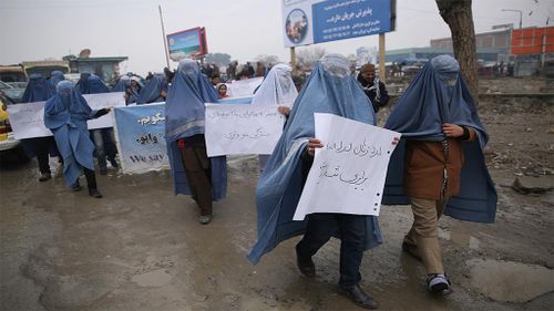 A group of men march through the streets of Kabul wearing light-blue burqas. (AAP)