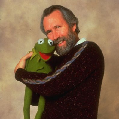 Puppeteer/creator of the Muppets Jim Henson standing with Kermit the Frog in his arms. 