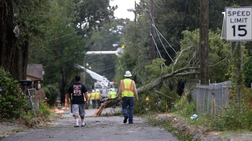 Workers clear trees from power lines in Biloxi, Mississippi. (AAP) 