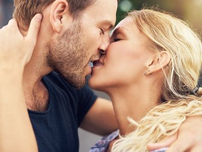 Young couple deeply in love sharing a romantic kiss, closeup profile view of their faces