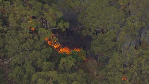 An out-of-control bushfire is burning dangerously close to homes in Melbourne's east as erratic winds and heatwave conditions are felt across the city.