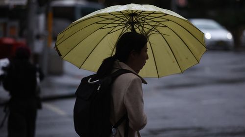 People are seen braving the rain on Friday, 23 May, 2025. The coastal trough responsible for bringing record rain to northern NSW has become more mobile after it was parked for days over soaked catchments. Picture - Sam Mooy / The Sydney Morning Herald