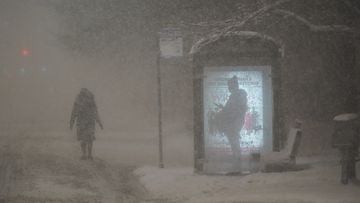 A woman walks to a bus shelter on Dr. Martin Luther King Drive as a man waits in the shelter during the pre-dawn hours Wednesday, Feb. 2, 2022, in Chicago. 