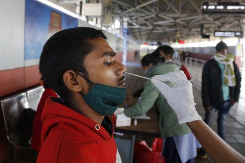 2021 年 12 月 3 日星期五，一名卫生工作者在印度艾哈迈达巴德的一个火车站从一名进入该市的旅行者身上采集拭子样本，以进行 COVID-19 测试。