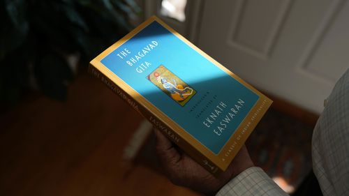 Mahendra "Mick" Patel shows a copy of the Bhagvad Gita he read while he was in jail.