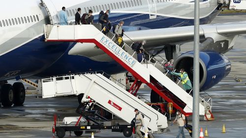 Passengers disembark a chartered flight Melbourne Airport in April, before becoming some of the first to be sent to hotel quarantine.