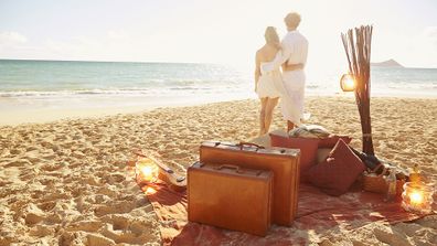 Caucasian couple with suitcases on tropical beach