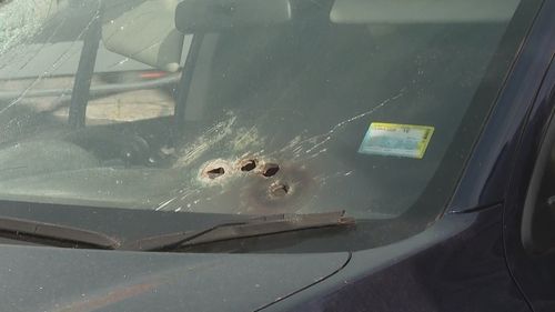 Um carro com vários buracos de bala no para-brisa.