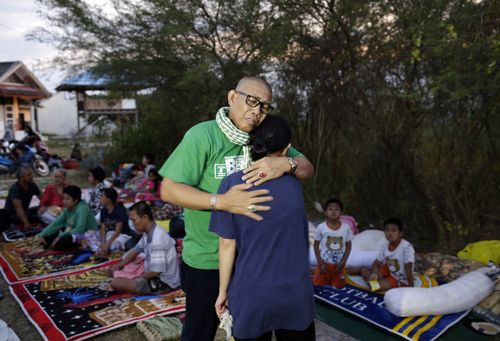 An Indonesian man hugs his daughter who survived the earthquakes and tsunami as they reunite at an open air camp in Palu.