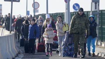 A Polish border guard assists refugees from Ukraine as they arrive to Poland at the Korczowa border crossing, Poland, Saturday, Feb. 26, 2022. (AP Photo/Czarek Sokolowski)