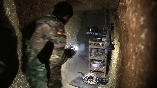 A peshmerga fighter walks through the kitchen of an underground tunnel made by ISIL fighters. (AAP)
