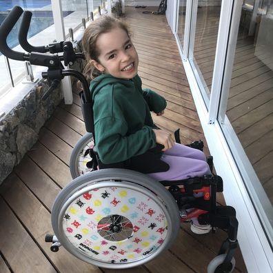 Eva Kalpidis grins sitting in her wheelchair.