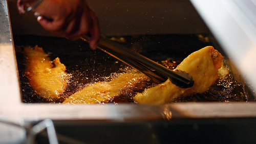 A chef turns a piece of fried fish in the fryer as it gets cooked, at Captain's Fish and Chip shop in Brighton on March 25.