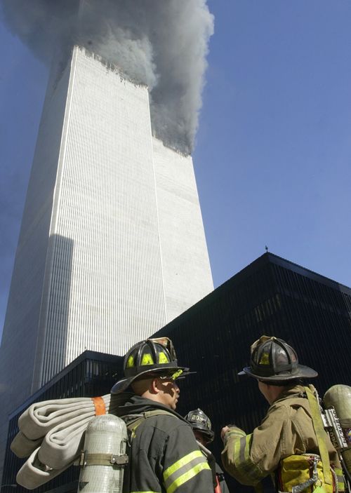 Firefighters watch as smoke pours from the twin towers of the World Trade Center after planes hit them in a terrorist attack. (Getty)