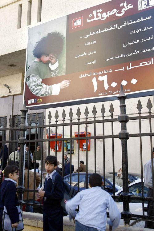 Egyptian children walk under a billboard, that is part of a national campaign to encourage families to stop circumcising their daughters.