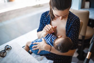 Mother breastfeeding her baby in public. They are sitting in a restaurant