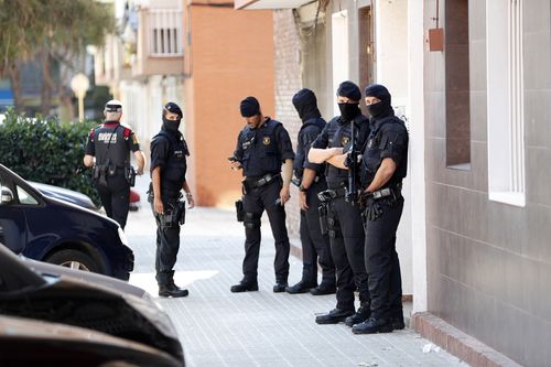 Several Mossos d'Esquadra officers stand guard outside the residential building where the man, who entered in a police station holding a knife and allegedly shouting 'Allah is great', lived in the town Cornella de Llobregat, in Barcelona, northeastern Spain