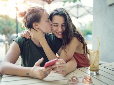 Young couple, two women, embracing and drinking iced coffee