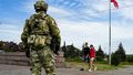A young couple walks past a Russian soldier guarding an area at the Alley of Glory in Kherson.