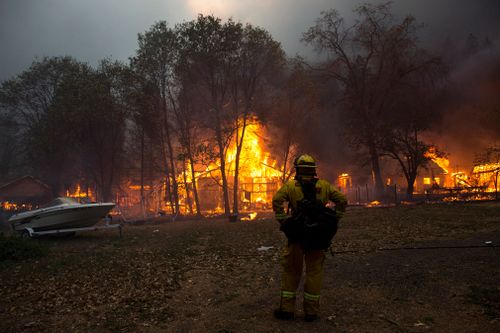 A fire fighter assesses the area as buildings are consumed by the Camp Fir.