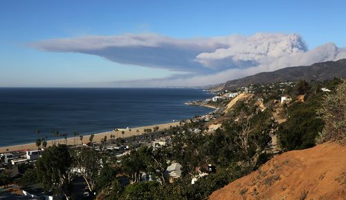 Strong winds blow smoke horizontally over the the Santa Monica Mountains and the Pacific Ocean over the city of Malibu.