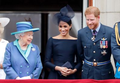 Queen Elizabeth, Meghan, Duchess of Sussex and Prince Harry, Duke of Sussex watch a flypast to mark the centenary of the Royal Air Force from the balcony of Buckingham Palace on July 10, 2018 in London, England. 