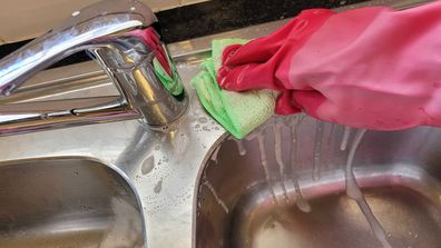 Woman scrubs kitchen sink clean to polish it