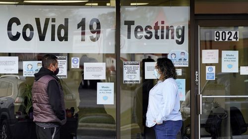 Exam Corp Lab employee, right, wears a mask while speaking to a patient in line for COVID-19 testing in Niles, Ill, on October 21, 2020