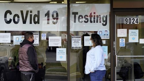 Exam Corp Lab employee, right, wears a mask as she talks with a patient lined up for COVID-19 testing in Niles, Ill on October 21, 2020