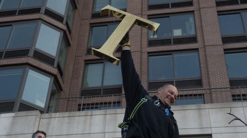 A workman triumphantly removes a "T" from the facade. (AFP)