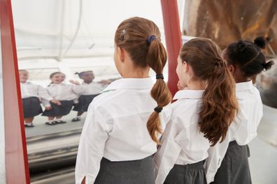 Schoolgirls looking in a curved mirror at a science centre