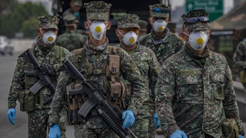 Filipino policemen wearing facemasks and gloves man a checkpoint as authorities begin implementing lockdown measures on March 16, 2020 in Las Pinas in Metro Manila.