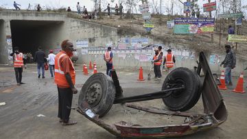 Volunteers stand near the wreckage of a bus that fell into a roadside ditch in Shibchar area in Madaripur district, Bangladesh, Sunday, March 19, 2023. 