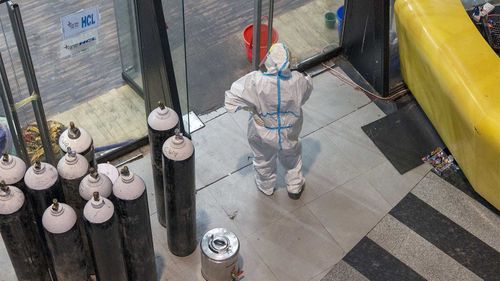 A health worker stands next to oxygen tanks at a COVID-19 health centre in New Delhi, India.