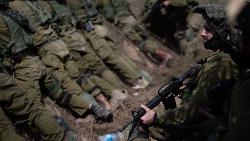 IDF soldiers guard an area around a kibbutz where dozens of civilians were killed days earlier in an attack by Hamas militants.