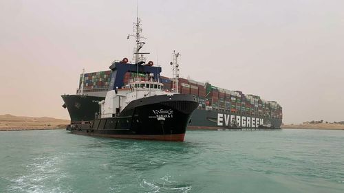 Ship stuck in Suez Canal looms over excavator working to free it