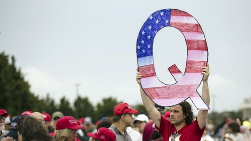 David Reinert holding a Q sign waits in line with others to enter a campaign rally with President Donald Trump and U.S. Senate candidate Rep. Lou Barletta, R-Pa., Thursday, Aug. 2, 2018.