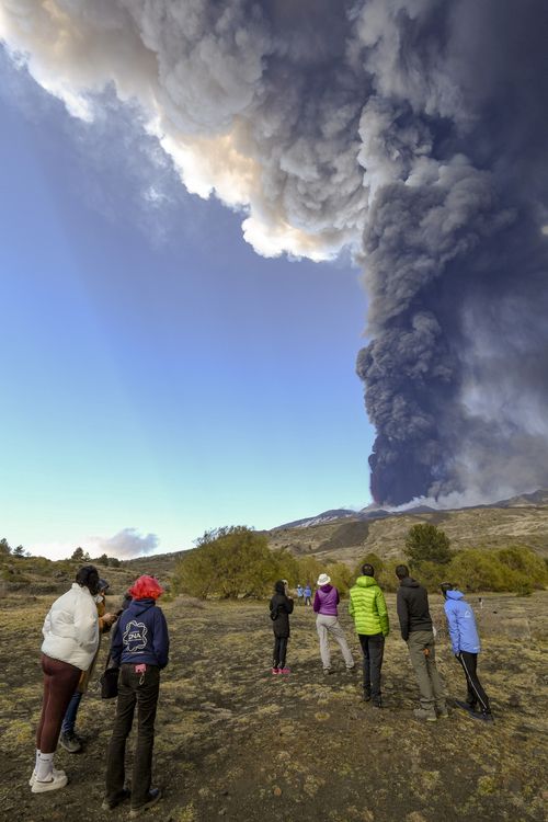 People look at volcanic ashes ascending from the south-east crater of the Mt. Etna volcano in Sicily, Italy, Monday, February 21, 2022. (AP Photo/Salvatore Cavalli)