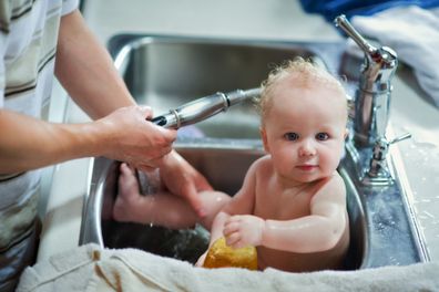 Baby having a bath in the kitchen sink