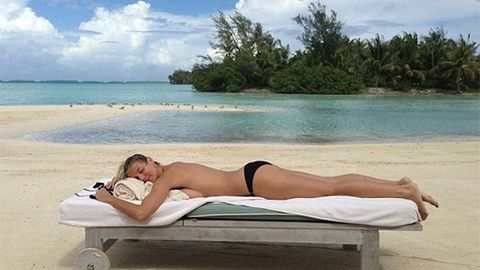 Heidi Klum sunbaking topless on an island