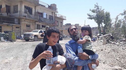 Locals in front of bullet-riddled homes in Mosul. (Owen Holdaway)