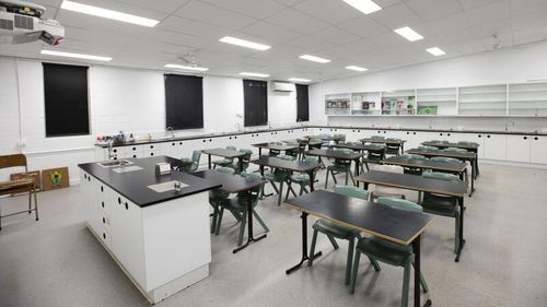 A classroom with white walls and black chairs and desks.