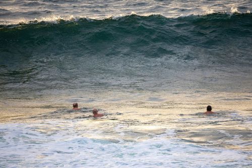 Os nadadores entram na água em uma praia fechada de Coogee na manhã de sexta-feira, um dia depois que um nadador desapareceu após ser arrastado para o mar. Sexta-feira, 2 de janeiro de 2026. Foto: Sitthixay Ditthavong